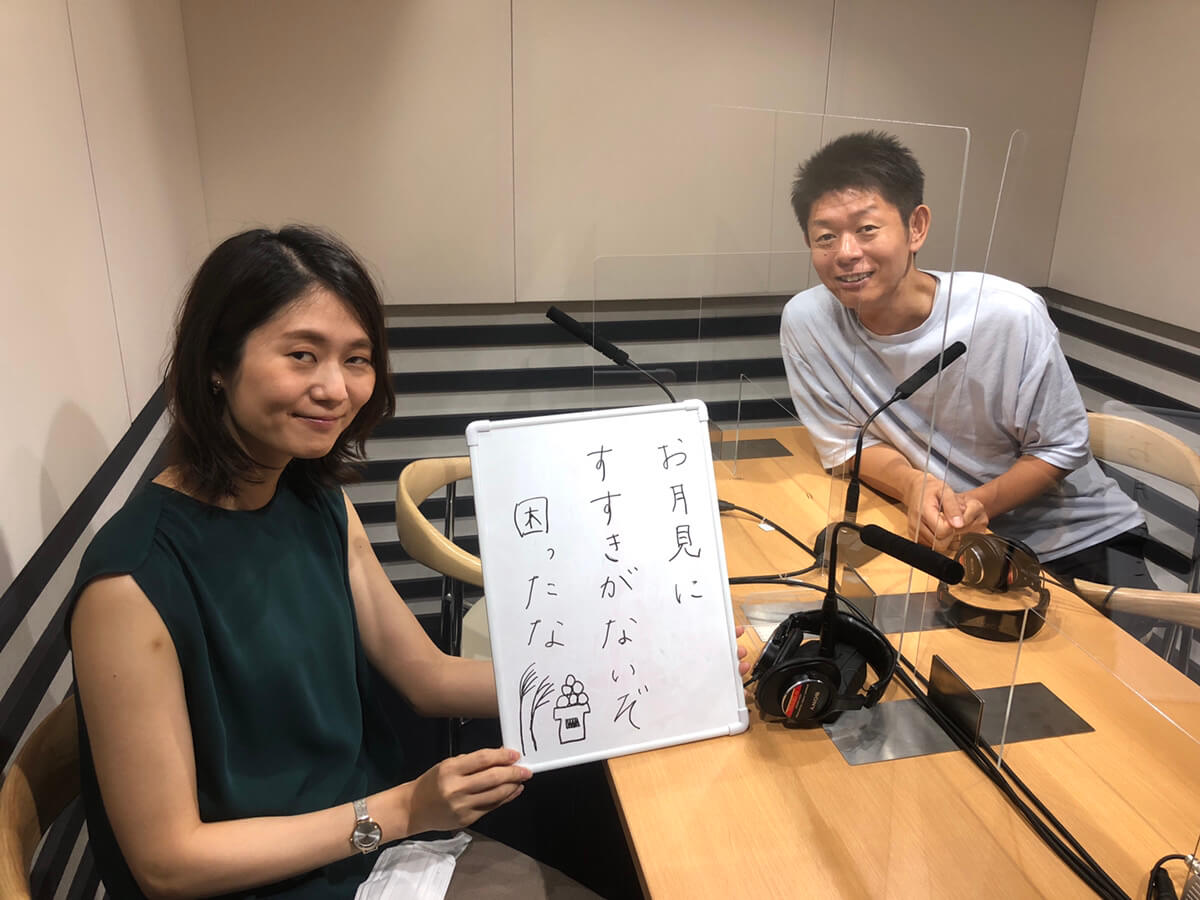 自作の俳句を書いたボードを持つ古藤由佳弁護士と笑顔の島田秀平さん