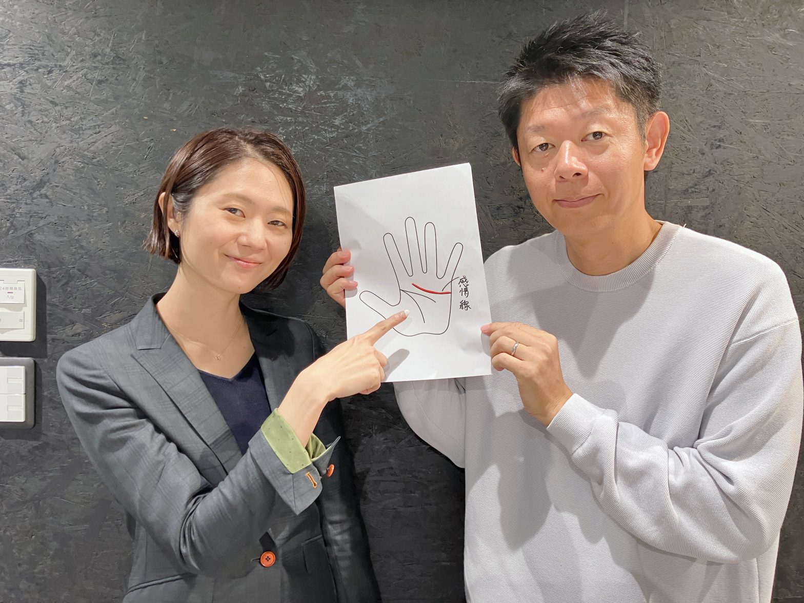 手相の感情線を紹介する紙をもった島田秀平さんと古藤由佳弁護士